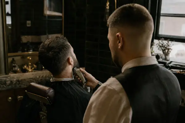 Barber trimmt im Barbershop den Bart eines Gastes